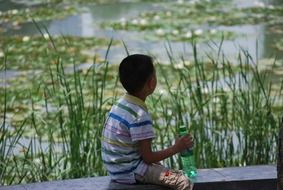 asian child boy sits at water