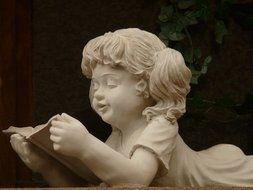 stone figure of a girl which read a book