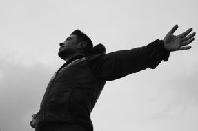 young man with wide open hands at sky