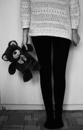 girl holding a toy bear black white photo