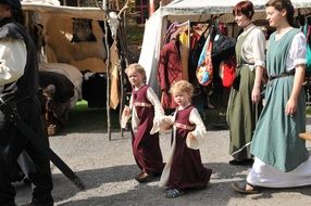 children and girls in medieval costumes on a city street