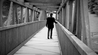 man on bridge black and white photo