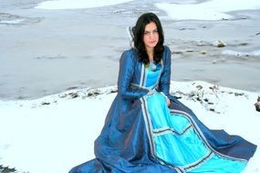 princess in a blue dress on a background of snowy nature