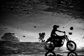 Black and white silhouette of a motorcyclist in a helmet on a background of abstract nature