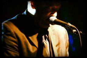 dark photo of a musician at the microphone on stage