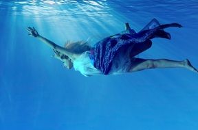 long haired girl swimming dressed underwater