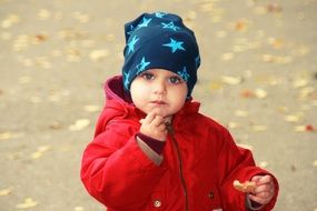 blue-eyed child eats while walking of park