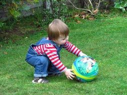 child plays with a ball in the park on green grass