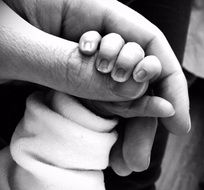 newborn holds mom by the finger