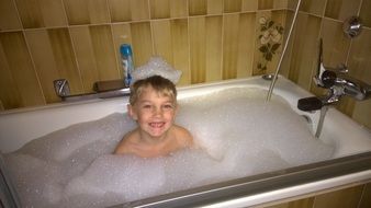 child bathing in bath with foam