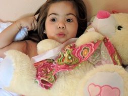 child girl with teddy bear in bad