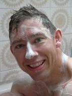 smiling young man with soap foam on face