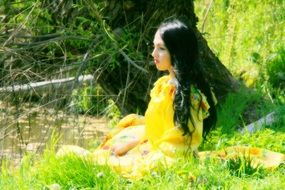 girl in a yellow dress on a green forest meadow