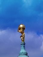 man holding a huge ball of gold sculpture