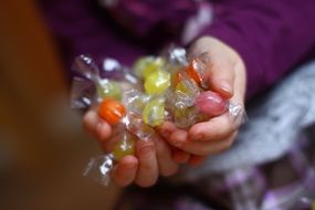 child holds a bunch of candies in his hands