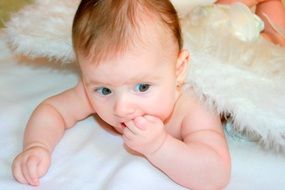 portrait of baby lies on a blue bedspread