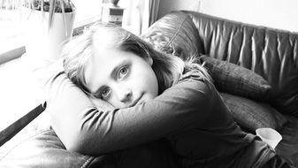 monochrome photo of girl is resting on a leather sofa