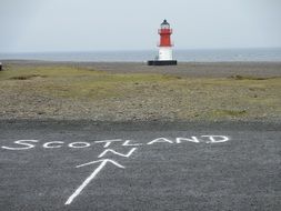 Sign and beautiful lighthouse on the shore in Scotland