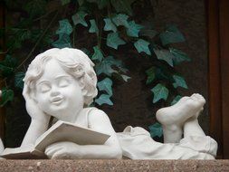 Stone figure of the boy who is reading the book