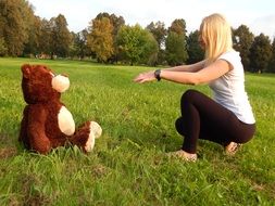 girl with big soft bear on grass