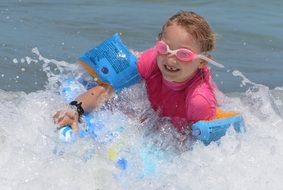 little girl is surfing in waves