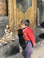 boy reads a prayer near a statue in Nepal