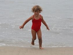 happy girl in swimsuit runs along the beach