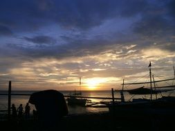 boats and people on beach at sunset