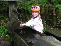 girl in a helmet at the water source