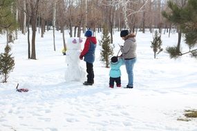 family near a snowman among nature