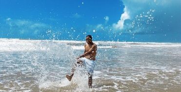 happy man in spray of water on the beach