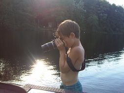portrait of boy with a camera on the lake