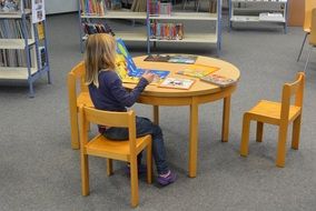 small Girl makes lessons in the library