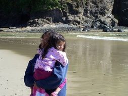 mother holding child girl on beach