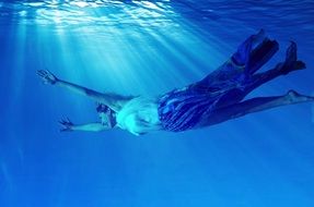 girl in a dress swims underwater