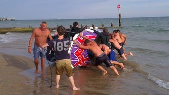 people at turned on side boat on beach