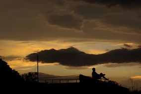 man sitting on a bench at dusk