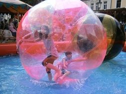 children in a ainflatable ball on the water