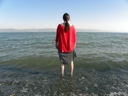 woman in a red jacket by the lake in Galilee