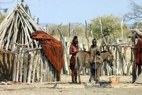 people near house from tree trunks in africa