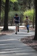 two boys running on path in park