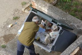 the homeless is rummaging in the bin