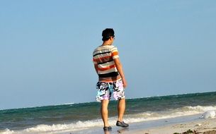 man walking on the beach on a sunny day