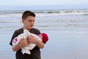 brother with a newborn sister on the beach