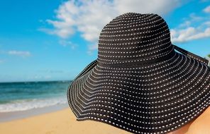 black hat person on beach ocean