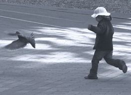 child with pigeons on a city street
