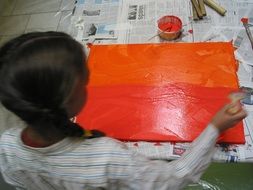 child paints with orange paint