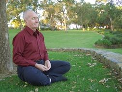 elderly man meditates in a park in Thailand