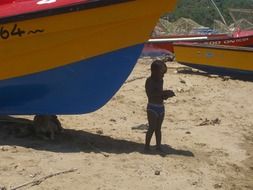 child near the boat on the beach