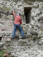 mountaineer climbs up the castle ruins